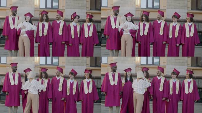 大学教授拥抱一群头戴毕业帽、身穿毕业斗篷的年轻人，祝贺他们顺利完成学业