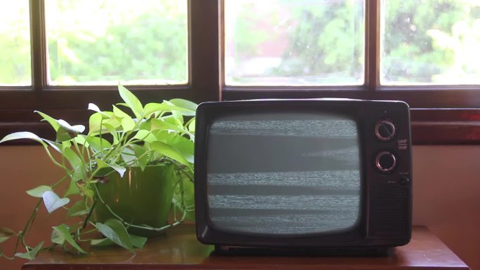 旧电视在房子的窗户上打开蓝屏。近距离，4K分辨率。
