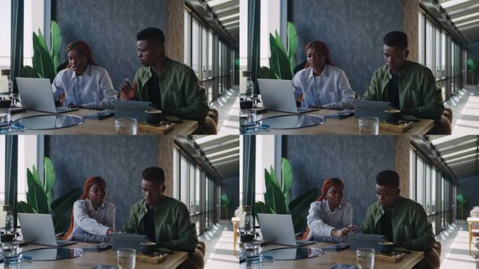 在一家咖啡馆里，两名黑人商业伙伴，一男一女，坐在一台笔记本电脑旁边，用手势强调自己的观点