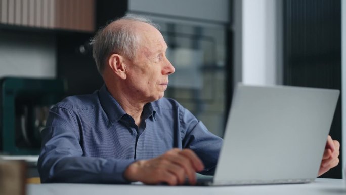 健康老人的画像，家里有笔记本电脑，祖父在看显示器