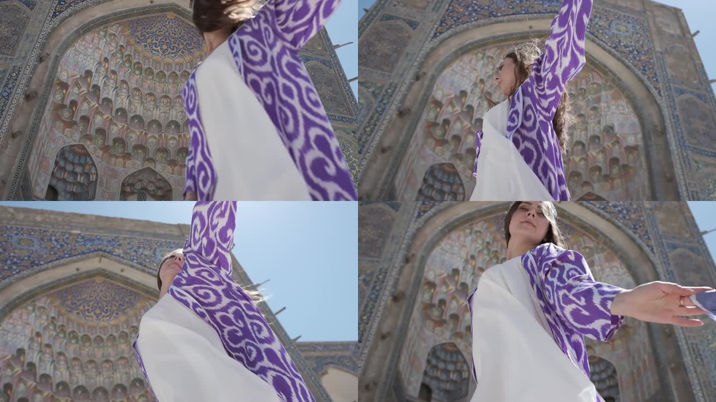 一位身穿东方长袍、头戴无边便帽、长发飘飘的年轻女子站在一座古老的清真寺附近