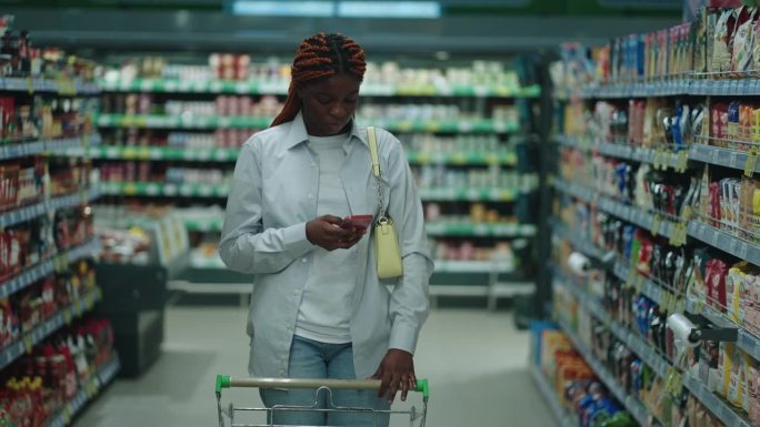 一名非裔美国妇女在超市购买新鲜农产品，她用电子设备帮助自己做出健康的选择
