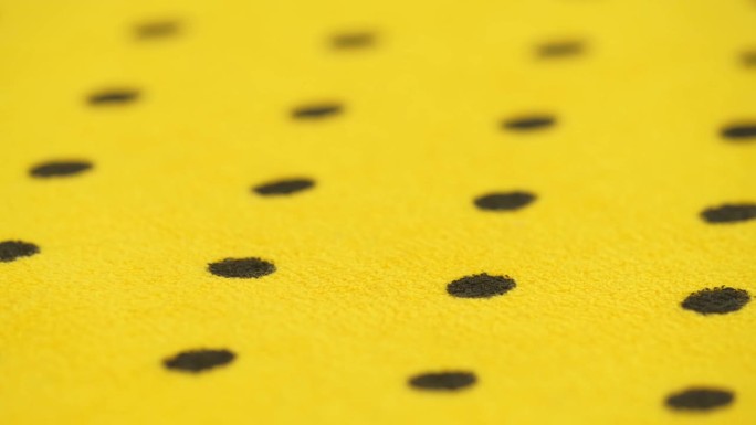 明黄色天然毛巾布，黑色圆点，旋转。抽象的背景。