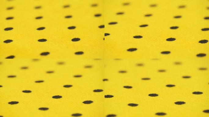 明黄色天然毛巾布，黑色圆点，旋转。抽象的背景。
