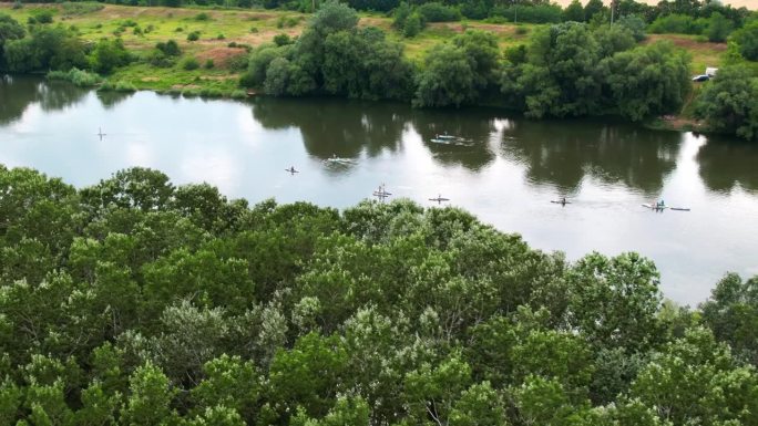 在摩尔多瓦的德涅斯特，无人机拍摄了多人站立冲浪的画面。河两岸是郁郁葱葱的森林