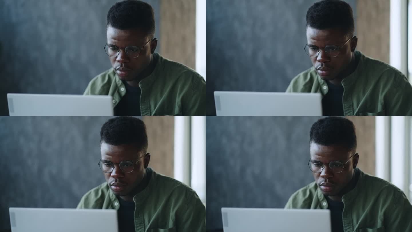 一位深思熟虑的年轻非裔美国创业公司创始人坐在咖啡馆的办公桌前，在笔记本电脑上寻找创新的商业解决方案，