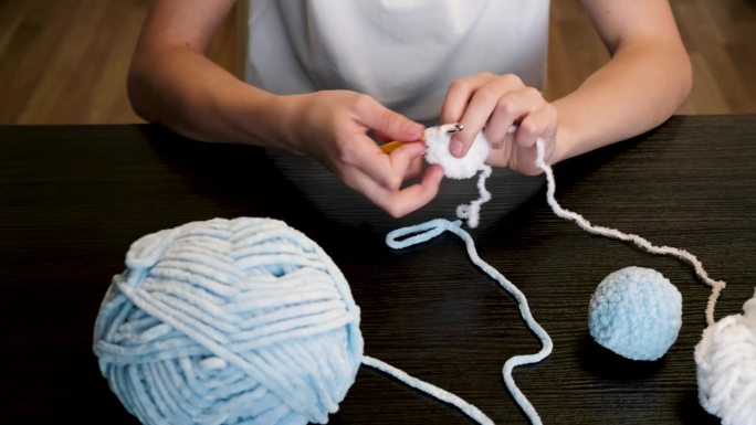 这个女孩一边编织，一边把线拉长。手工制作的。家里的爱好。