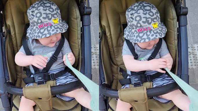 蹒跚学步的小男孩脱下衣服。这个孩子坐在婴儿车里拒绝穿袜子和脱衣服。1岁左右(11个月)