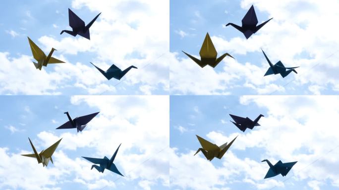 窗户上挂着五颜六色的折纸鸟鹤，映衬着天空。纸鸟似乎会飞。日本风格的折纸鹤是幸福和繁荣的象征。