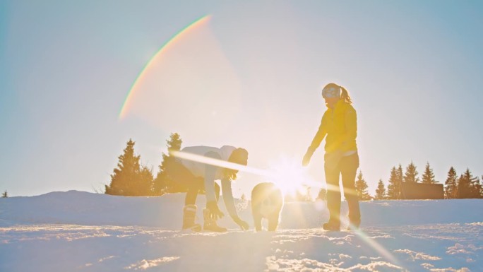 两个女人和她们的狗在雪坡上玩得很开心