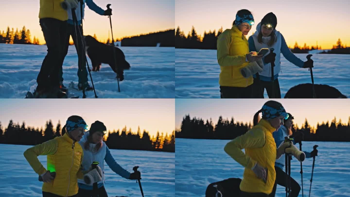 黄昏时分，两名妇女在乡下雪地上走雪鞋，一边看手机