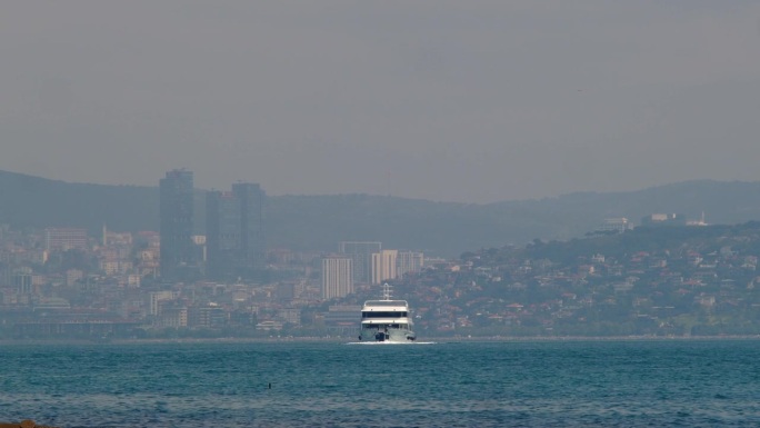 一艘客轮在这座现代化大都市的背景下驶向大海。一艘船在土耳其伊斯坦布尔的博斯普鲁斯海峡。都市风格。工作