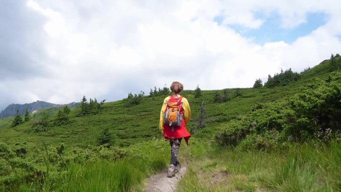 徒步旅行的女孩走在山间小路上