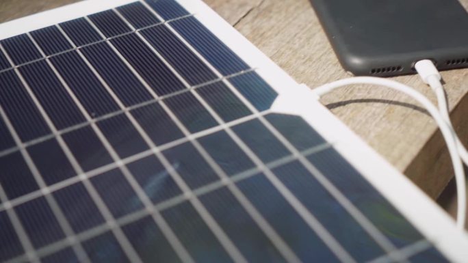 用便携式太阳能电池板给智能手机充电。露营。