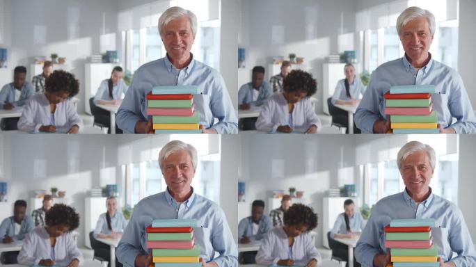 上了年纪的男老师拿着一摞书，在课堂上对着镜头微笑