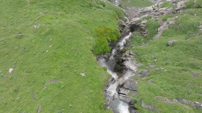 空中无人机看到的河流和瀑布流经绿色的高山牧场