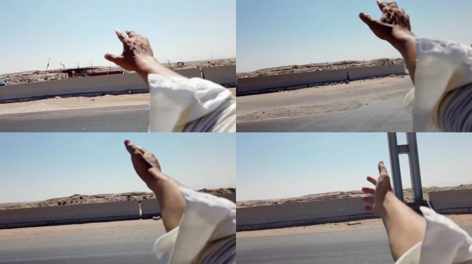 在埃及沙漠的高速公路上，男子伸出车窗，注视着沙漠
