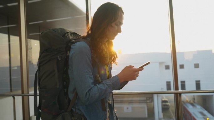 一名女子带着智能手机和背包走在机场航站楼