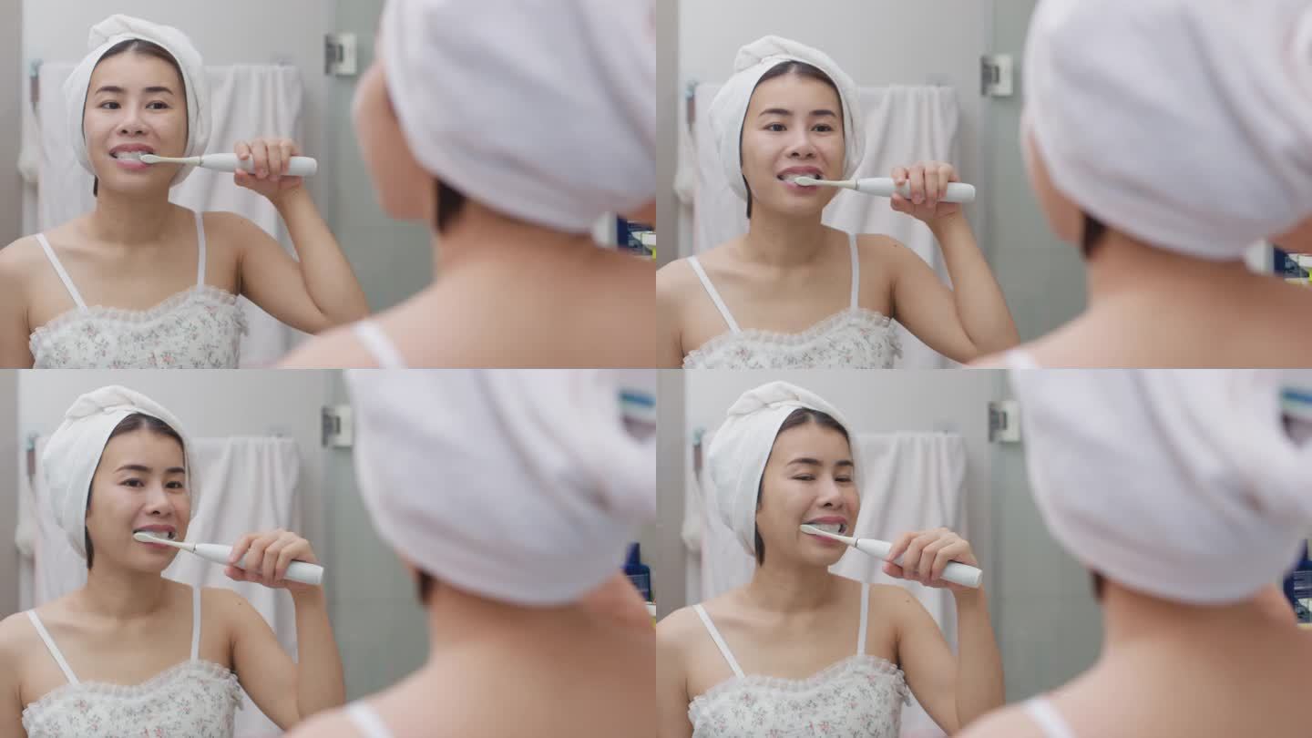 美丽的亚洲女人在浴室的镜子旁刷牙