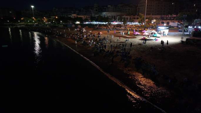 夜晚围观在海边的群众和城市建筑