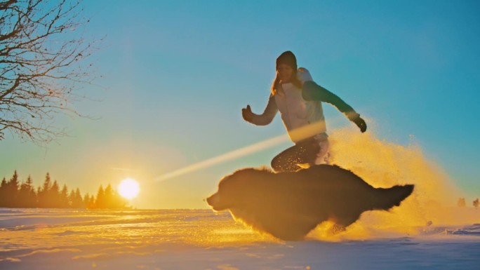 一名女子穿着雪鞋带着她的狗在雪地上奔跑