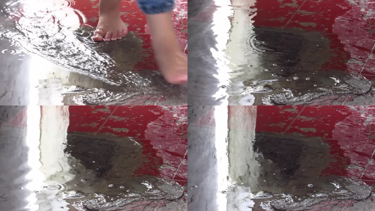 人的脚与聚集在红色地板上的雨水玩耍的特写镜头，高清镜头。在水坑里玩得开心。