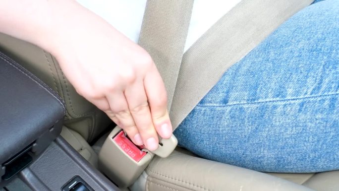 在汽车特写中，女性的手系紧安全带。
