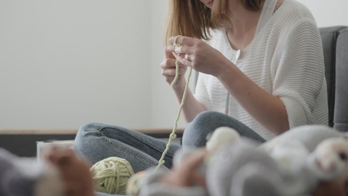 一名妇女正在休息，编织amigurumi，这是一种柔软的纺织品玩具，不仅可以安慰孩子，而且可以使房子