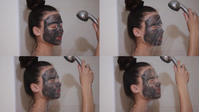 女人在淋浴时洗脸上的木炭面膜，慢镜头