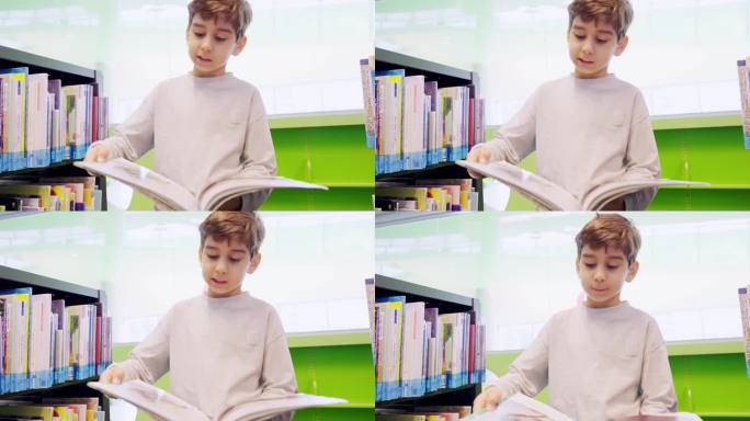 可爱的白人小男孩在图书馆的书架旁看书。