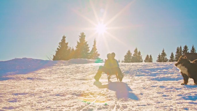 两个女人和一只狗在雪坡上滑下雪橇，玩得很开心