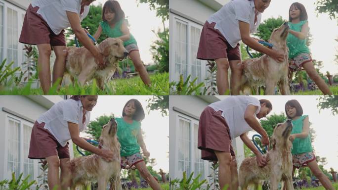 一个亚洲家庭，母亲和女儿在家里的花园里给狗狗洗澡。