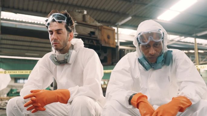 两名科学家坐在受感染的工厂区域，感到压力和疲惫