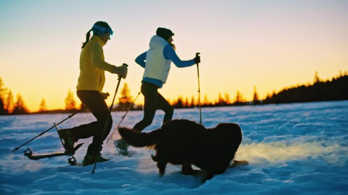 黄昏时分，两个女人在雪坡上走雪鞋