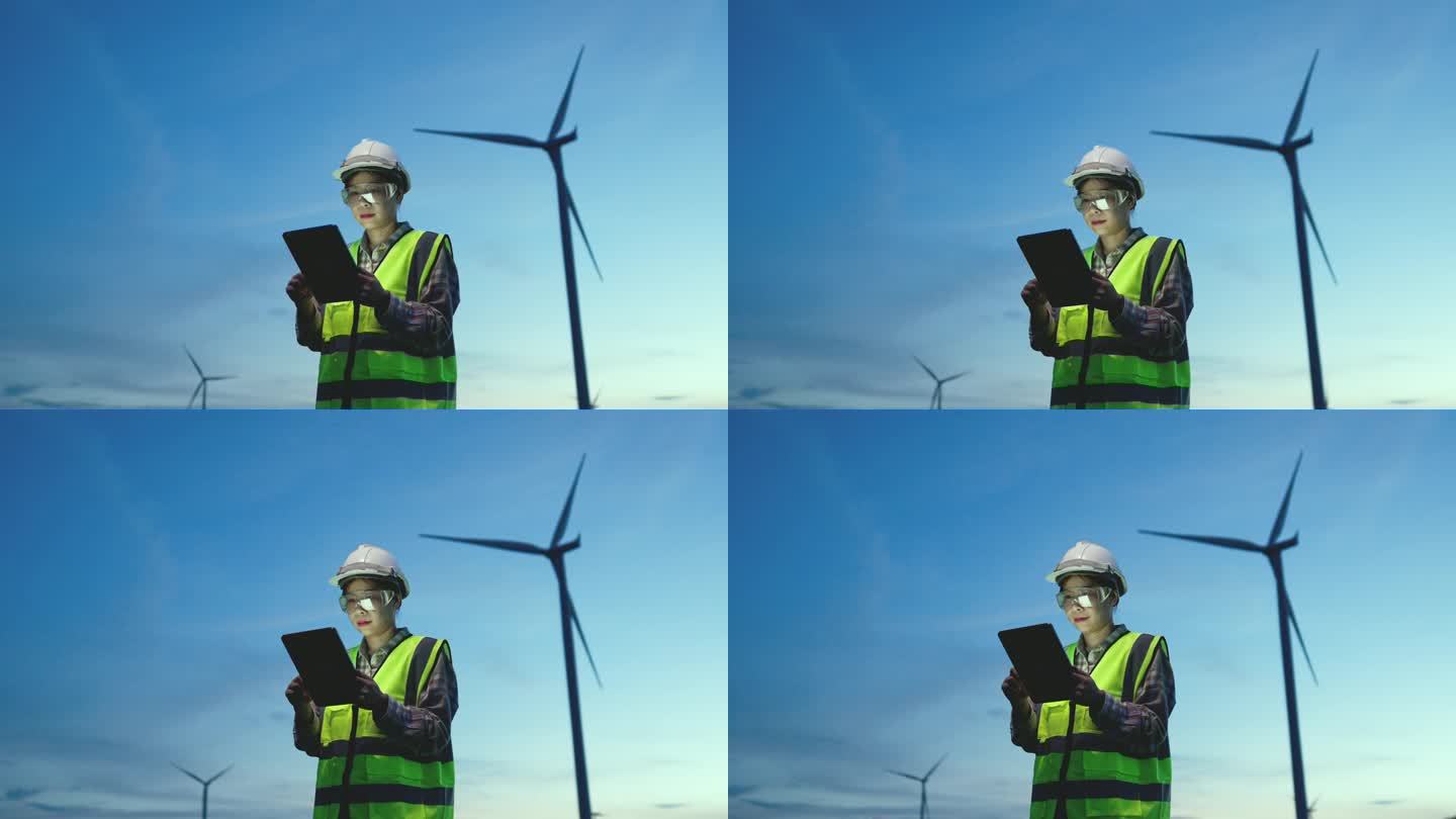 风车女工程师在数字平板电脑上观看风力涡轮机的运行