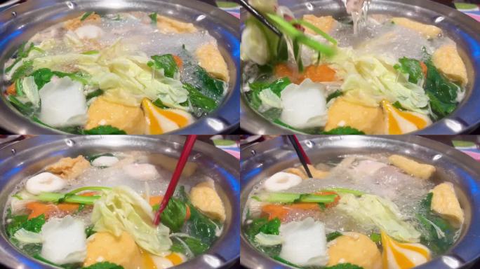 吃自助火锅。人们用手从火锅中挑选食物，吃寿喜烧或涮锅。