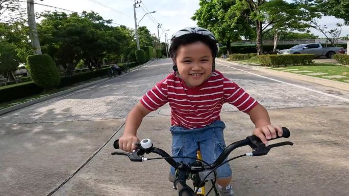 亚洲孩子在小区和跑道上练习骑自行车和踏板车。爱好和休闲的概念