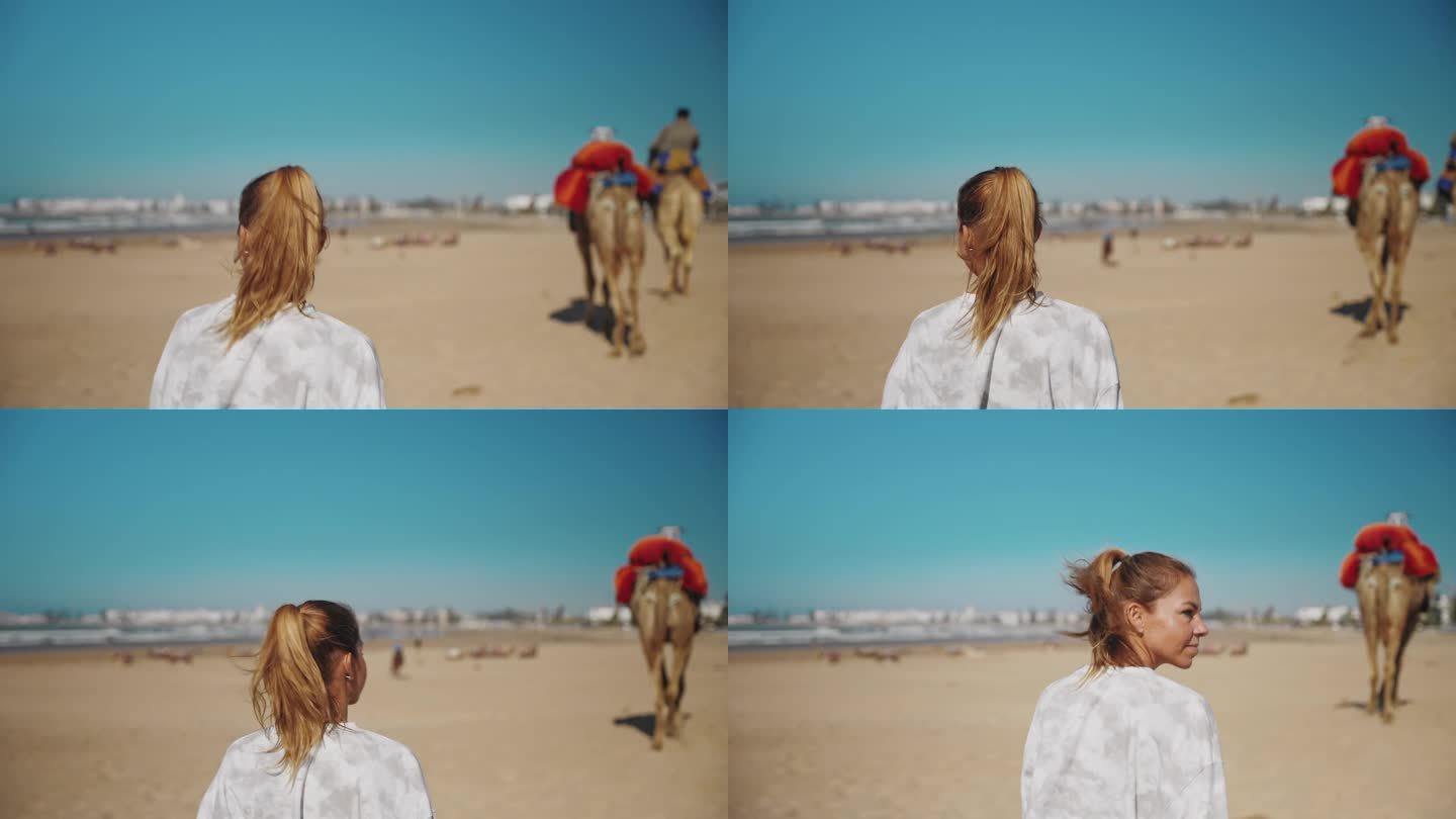 女游客走在沙滩上，两头骆驼在她前面