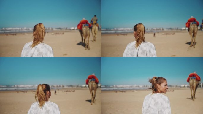 女游客走在沙滩上，两头骆驼在她前面