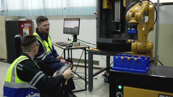 男工程师在工厂检查运行中的机器人的工作过程