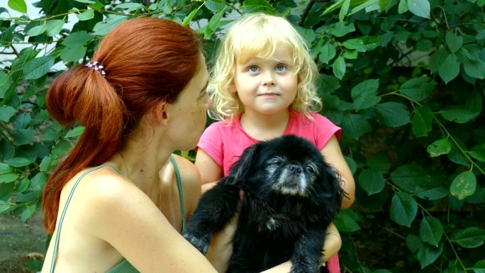 妈妈、女儿和宠物黑色的小狗金发可爱的小孩