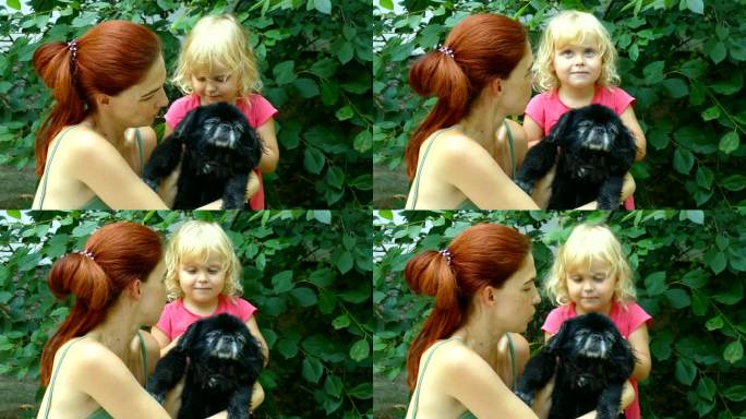 妈妈、女儿和宠物黑色的小狗金发可爱的小孩