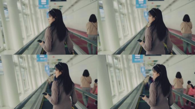一名亚洲妇女在候机楼准备继续她的旅程。她站在人行道上望着天空