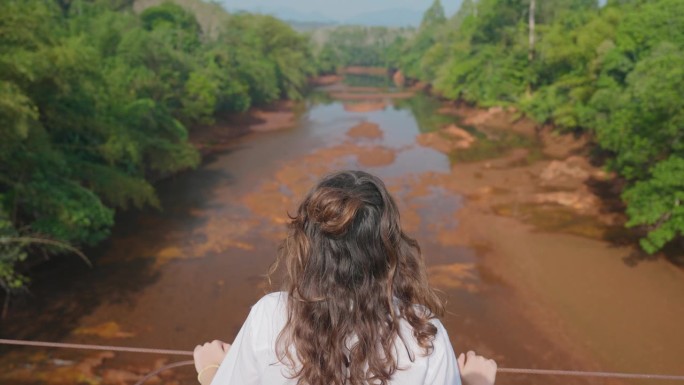 在考锅国家公园，站在桥上看热带河流的女子