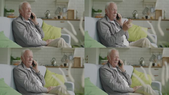 老人坐在舒适的公寓里的沙发上，用手机聊天，露出惊讶的微笑