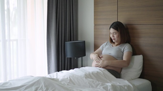 在家里的卧室里，怀着肚子里的宝宝的孕妇有一种爱的感觉和幸福