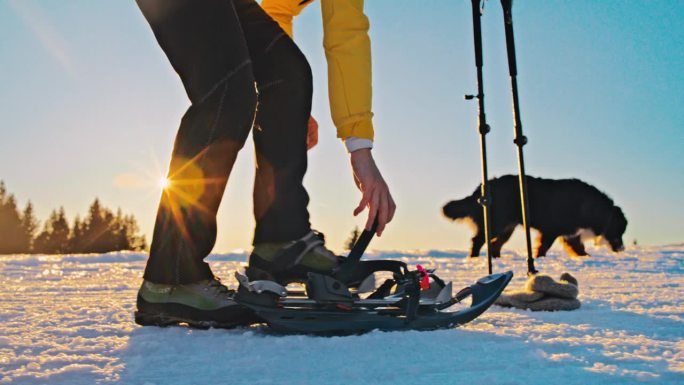 女徒步旅行者把雪鞋系在脚上