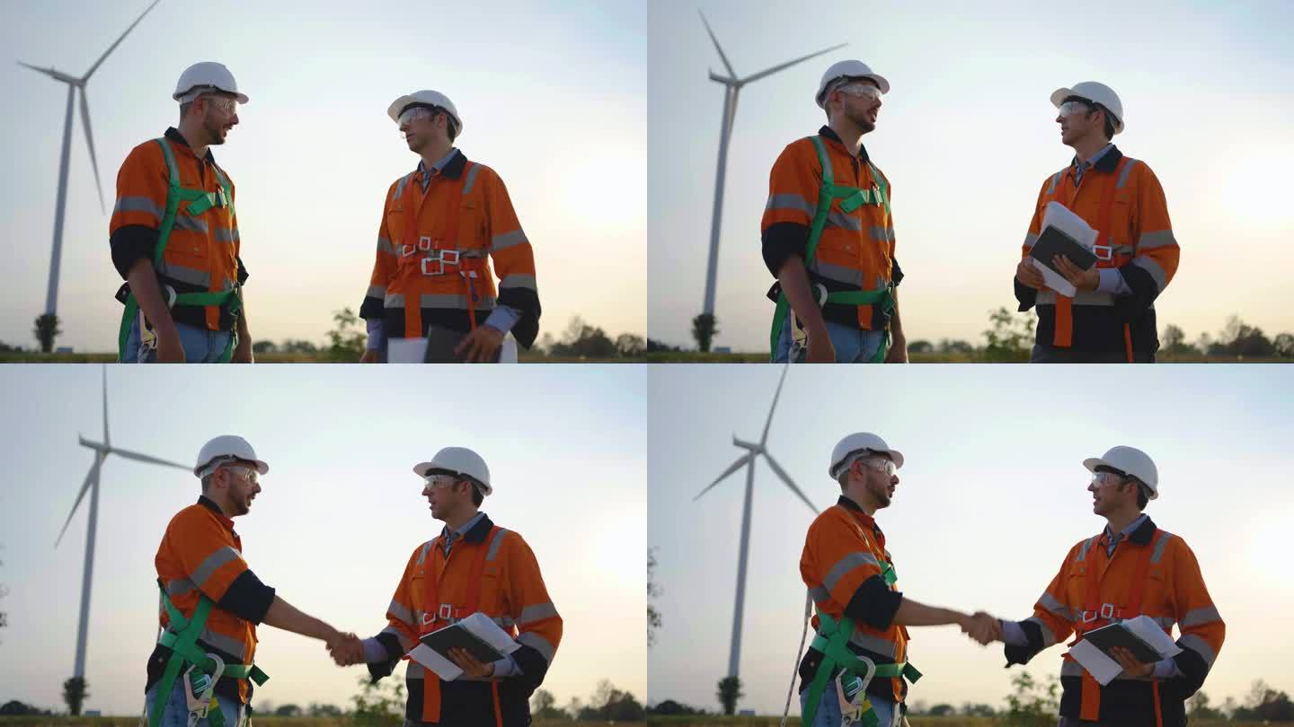 两位戴着安全帽和护目镜的白人工程师在日落前用风力涡轮机在农田里工作，他们握手道别，风力涡轮机发电