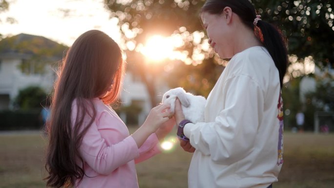 可爱的妈妈和女儿在他们的怀抱中享受着可爱的兔子。