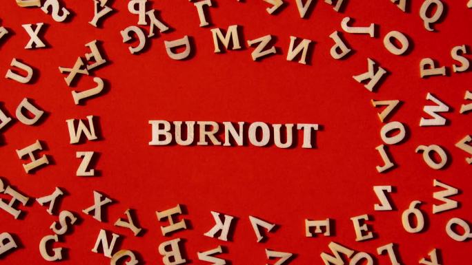 在明亮的红色背景上用木制字母制作的Word BURNOUT。励志话语引用概念。